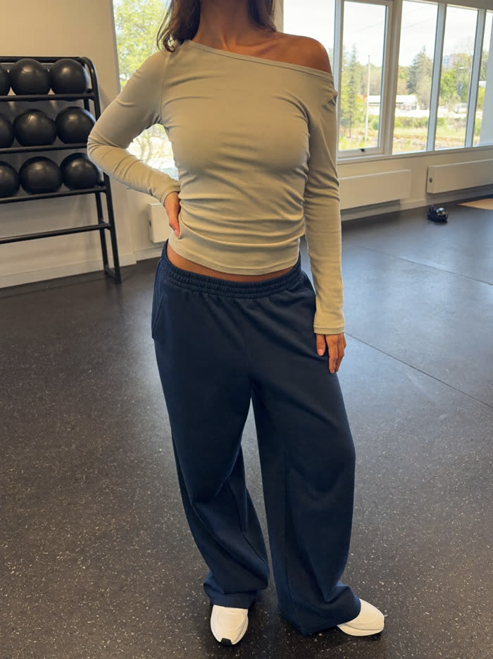 Woman in a stone long-sleeve top and navy wide-leg joggers