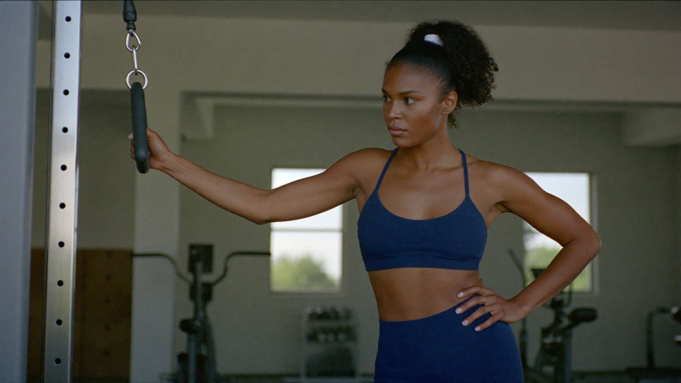 Woman training at a cable machine in a navy sports bra and leggings